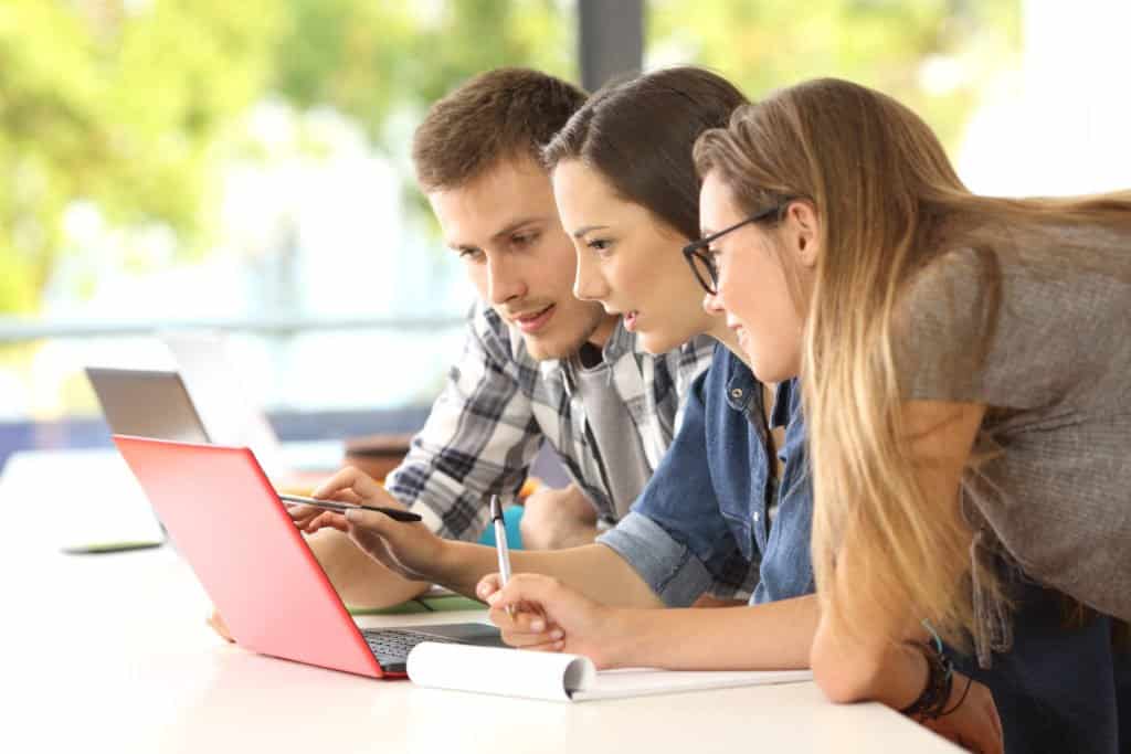 a man and 2 women looking at a laptop