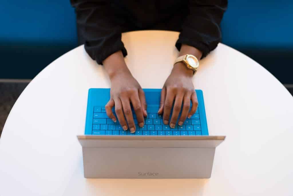 a person's typing on a blue laptop
