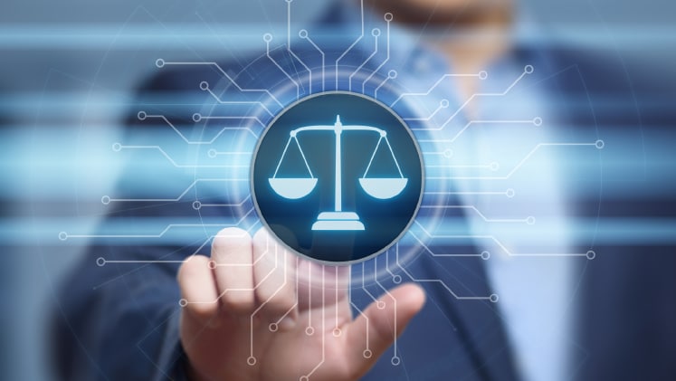 A man points at a blue digital screen showing the scales of justice