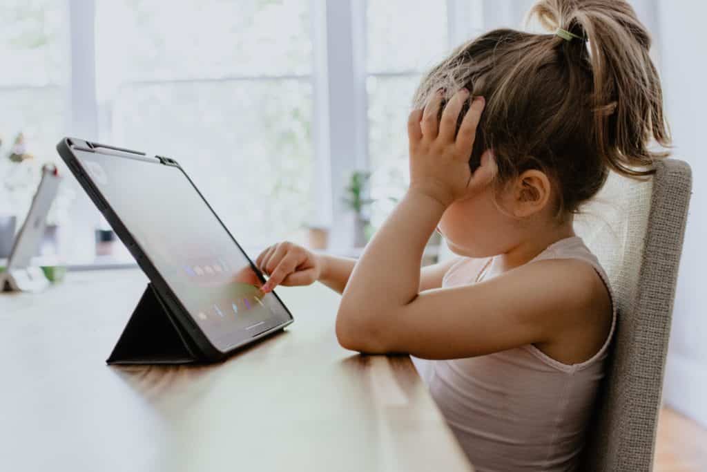a young girl sitting on the table and using her tablet
