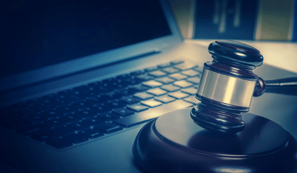 closeup of gavel in front of a laptop with focus on the gavel