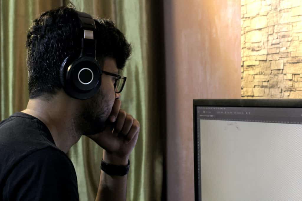 man with his headset looking at a monitor with his hand on his chin