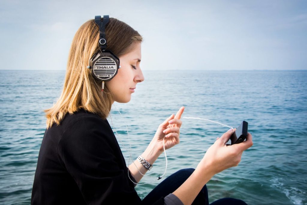 person meditating near the ocean with her headphones on