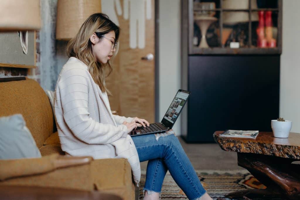 woman sitting on a coffee table working on a laptop on her lap