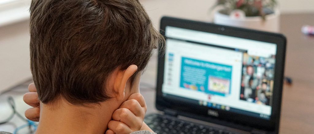 Image of a child looking at their laptop screen.
