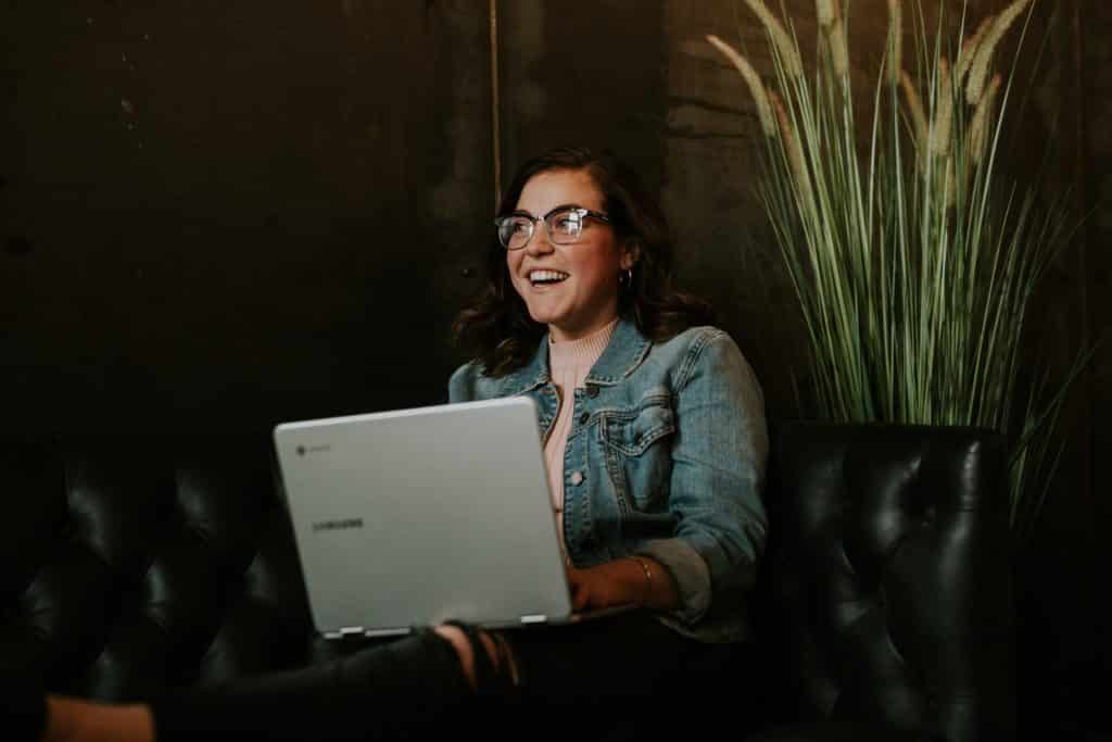 A woman sitting on the couch with a laptop on her lap conducting distance learning
