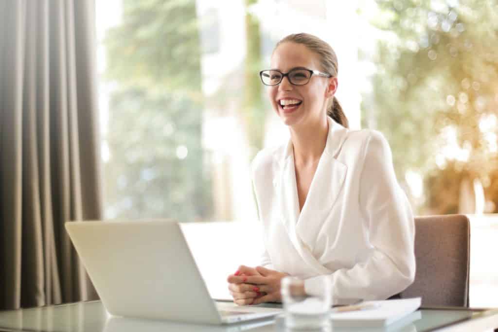 a woman sitting in front of her laptop smiling