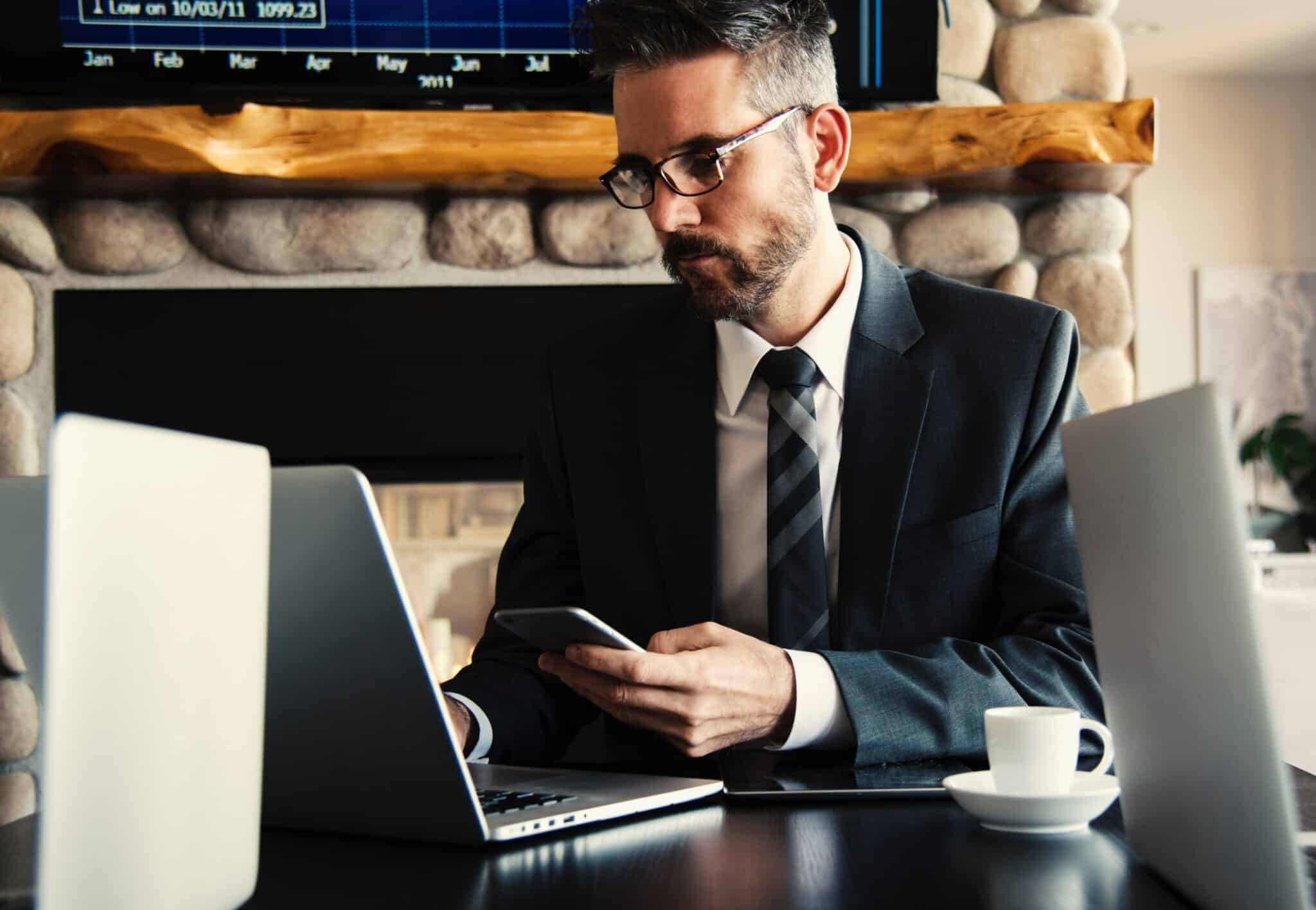Man in a business suit drinking coffee and working on a laptop computer