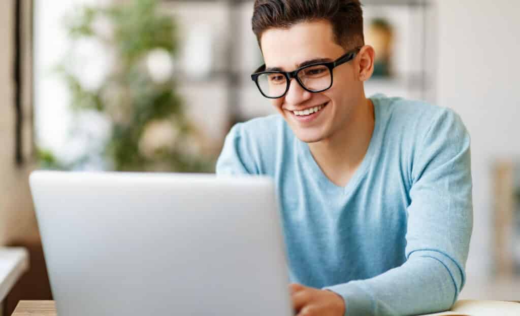 man wearing glasses looking at his laptop