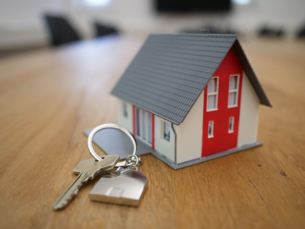 miniature house and normal sized house keys on a table