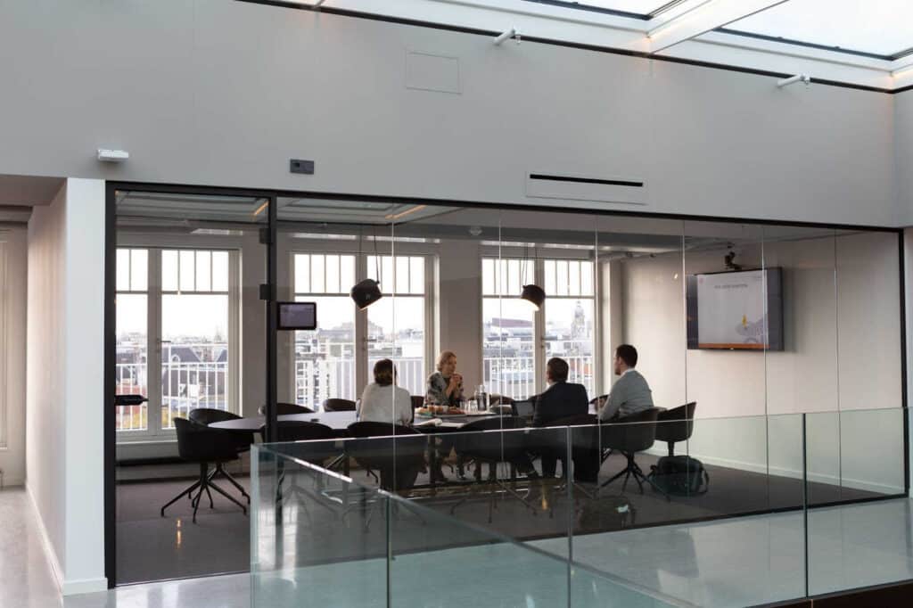 people sitting in a conference room with glass walls