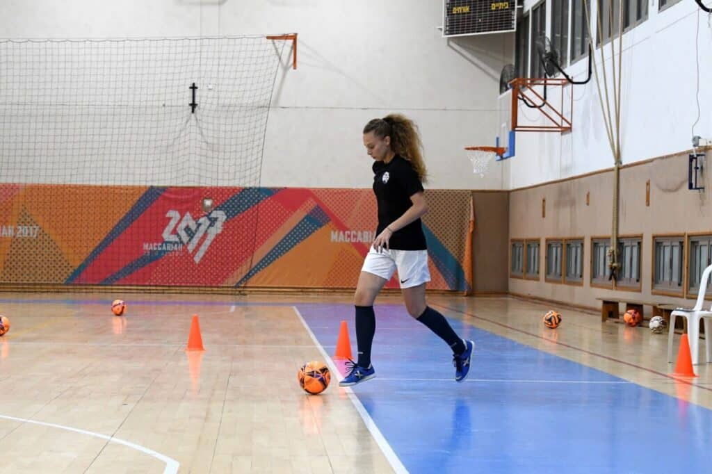 Player kicking an orange futsal ball