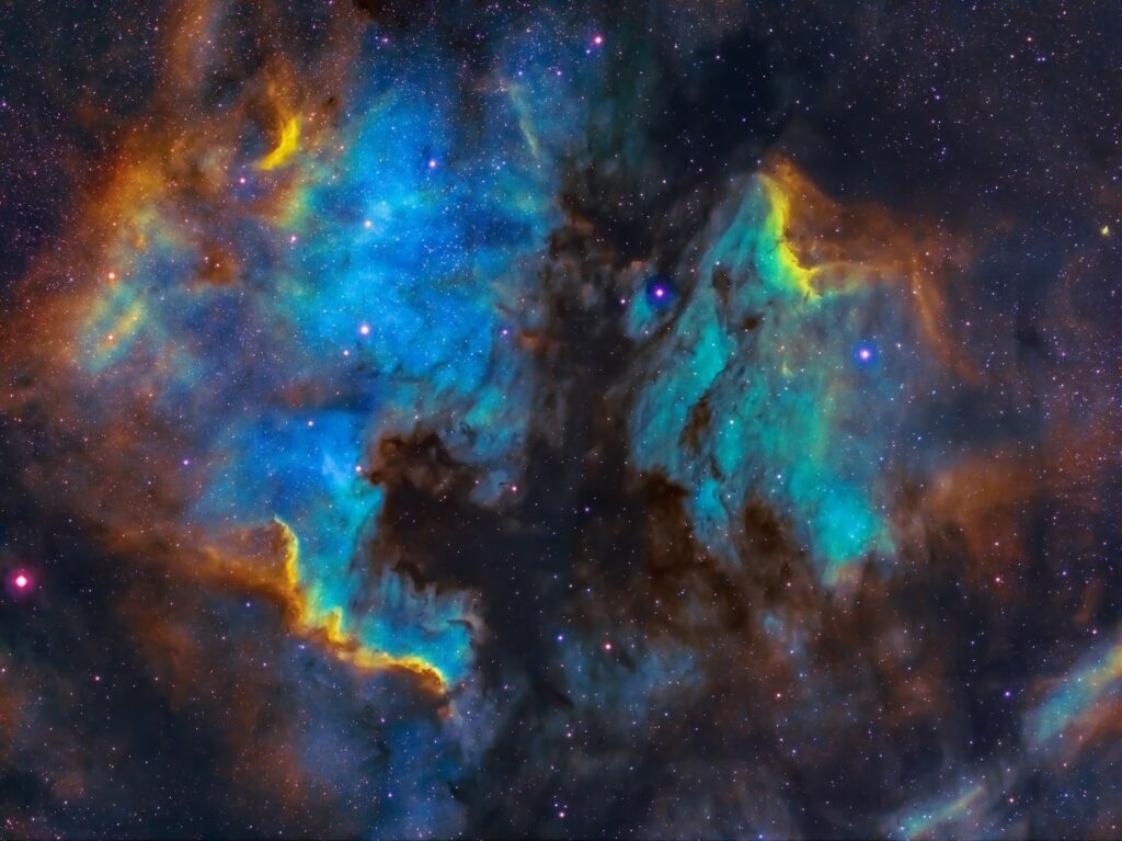 a brightly colored nebula in blue, teal and yellow against the backdrop of many points of light