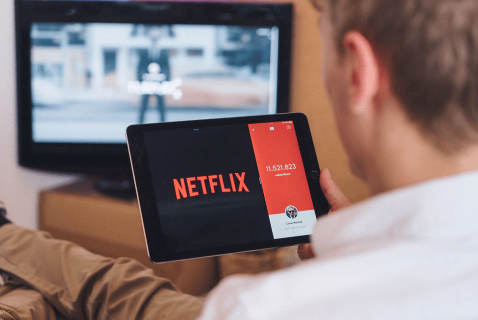 man holding up a tablet with the netflix application logo on screen