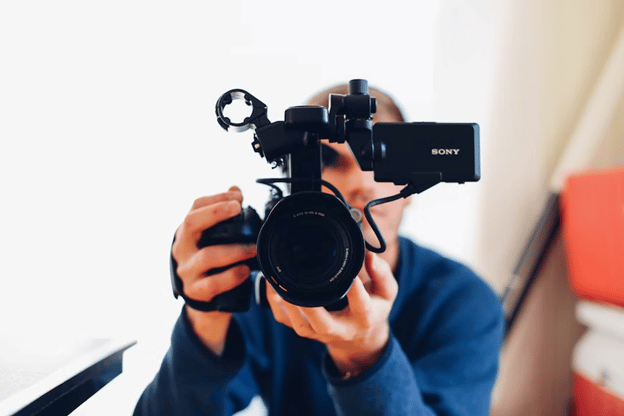 man in a blue shirt holding up a camera