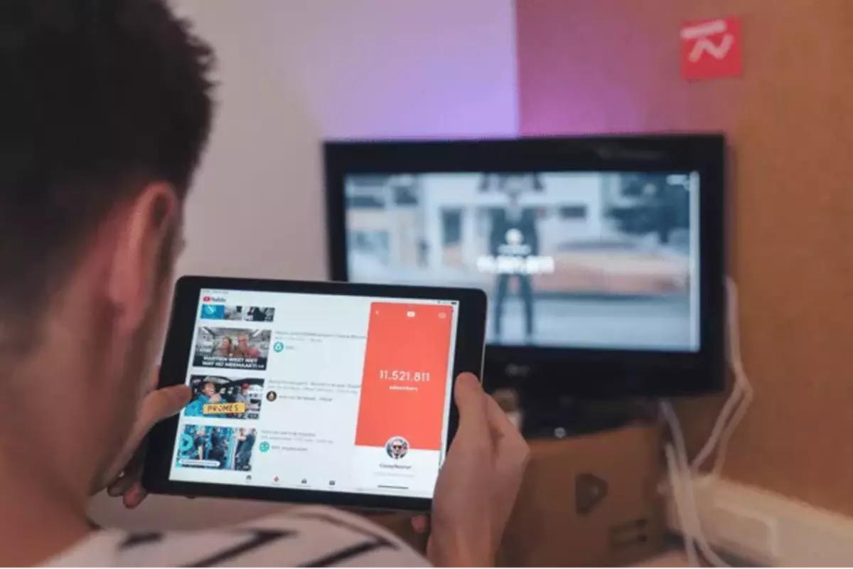 man holding his tablet up watching videos on youtube
