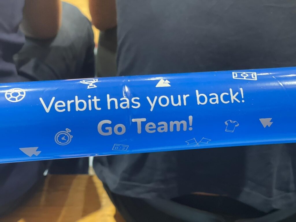 a Verbit cheering stick that says "Verbit has your back! Go Team!"