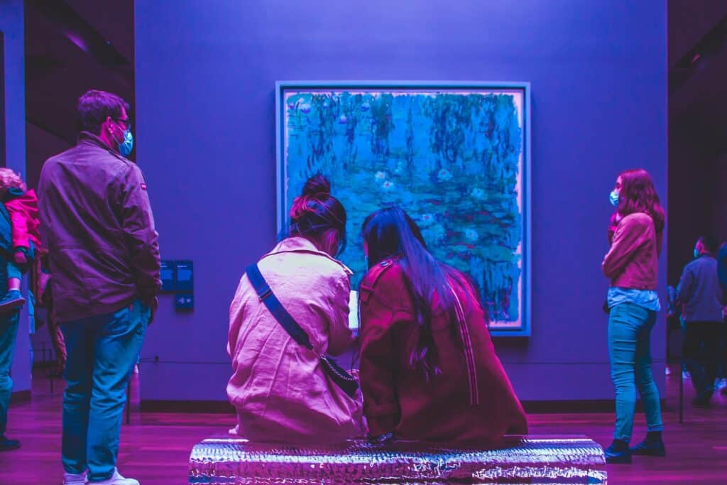 Visitors viewing artwork in an exhibit with blue lighting