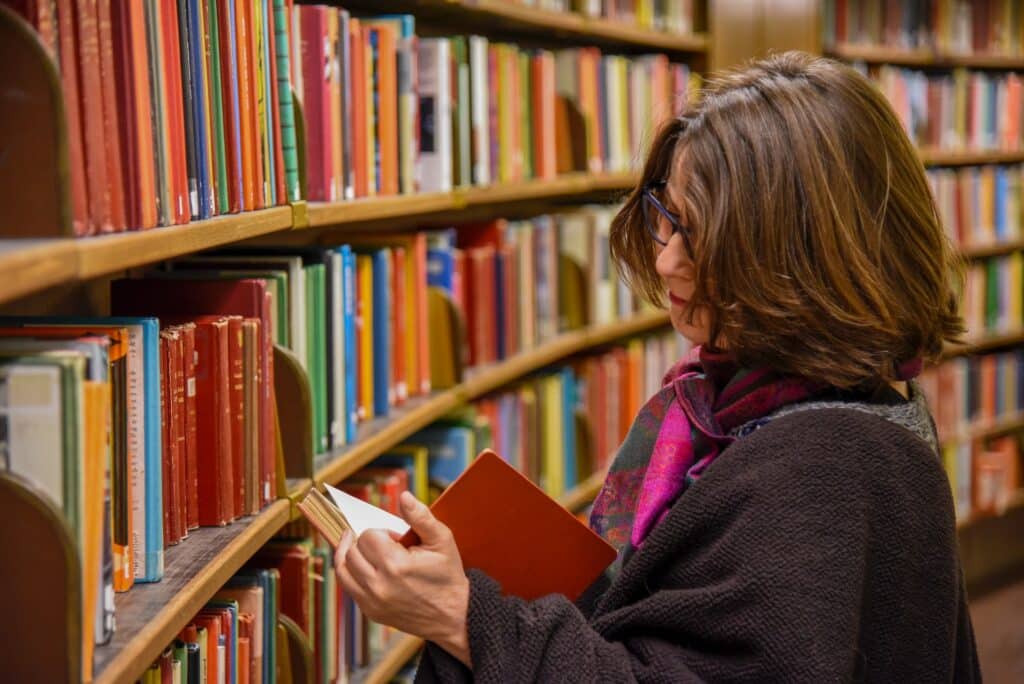 Woman looking at an orange book in a library