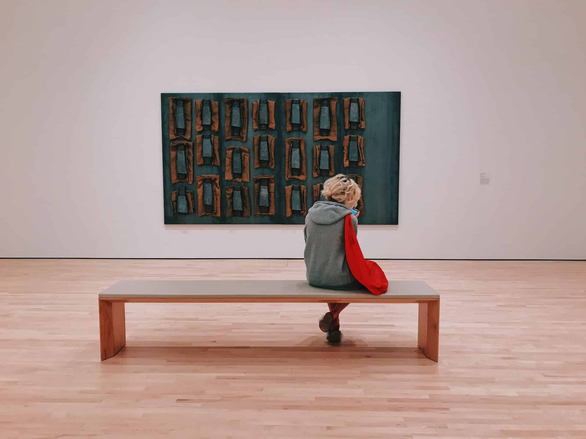 Woman on a museum bench in front to an abstract painting