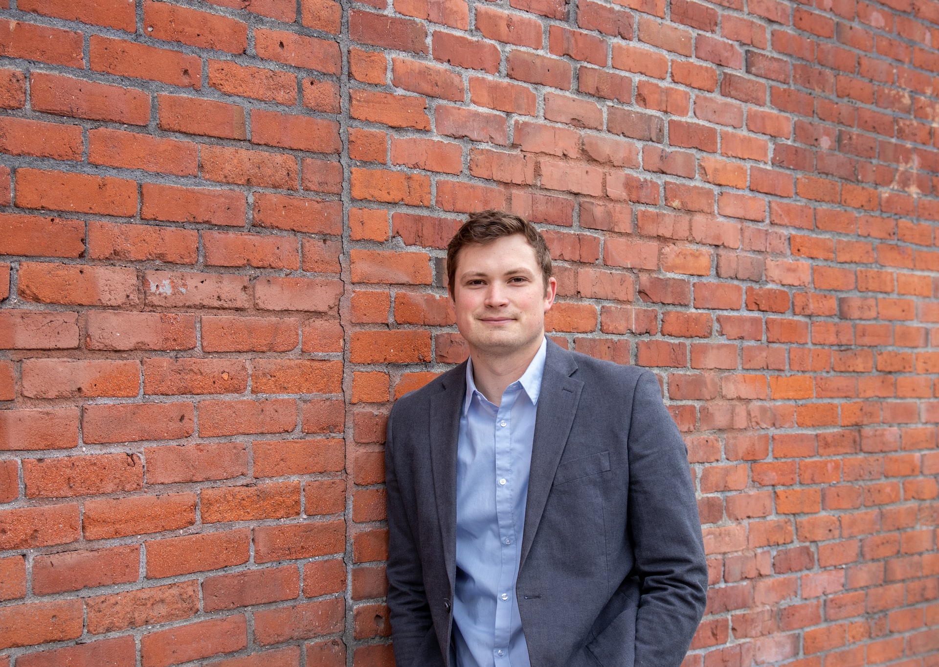 man in suit in front of a brick wall