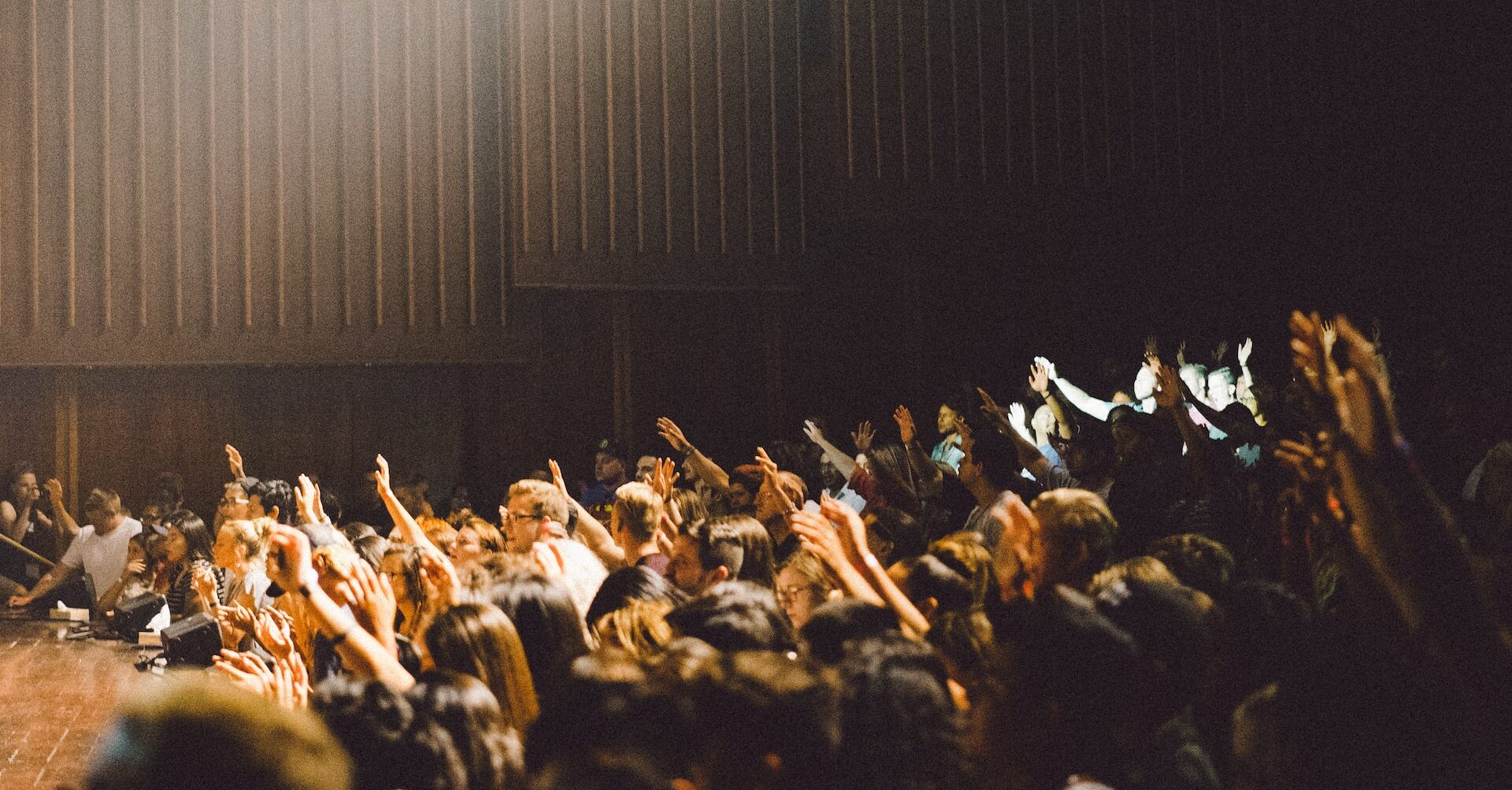 auditorium with people raising their hands