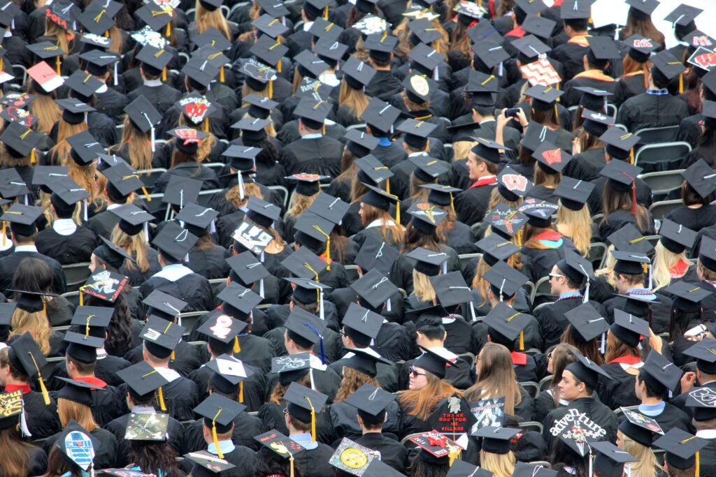 A large group of students in graduation attire, many with decorations in their caps.