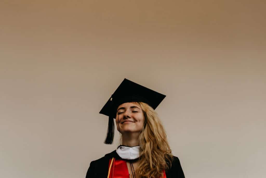 young woman in graduation attire smiling and closing her eyes