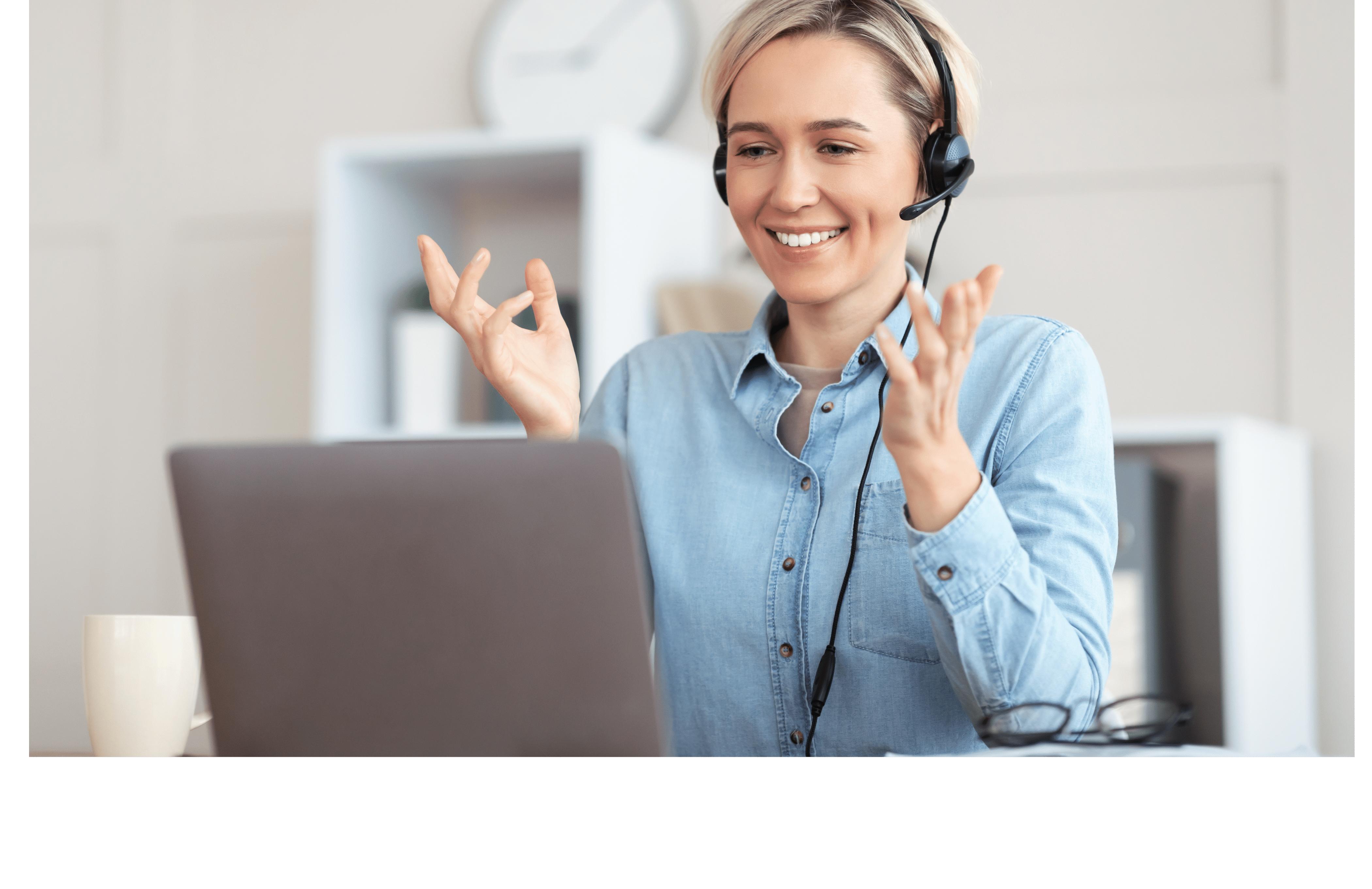 smiling woman wearing a headset and working on a computer
