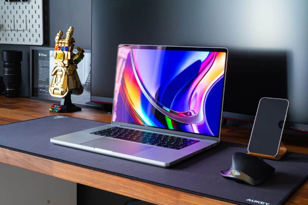 A desk with a robot arm and a computer with bright colors on the screen