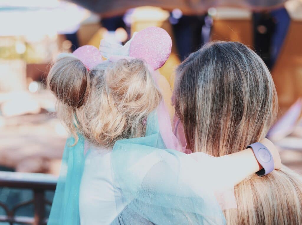 mother holding a daughter wearing pink Mickey ears.