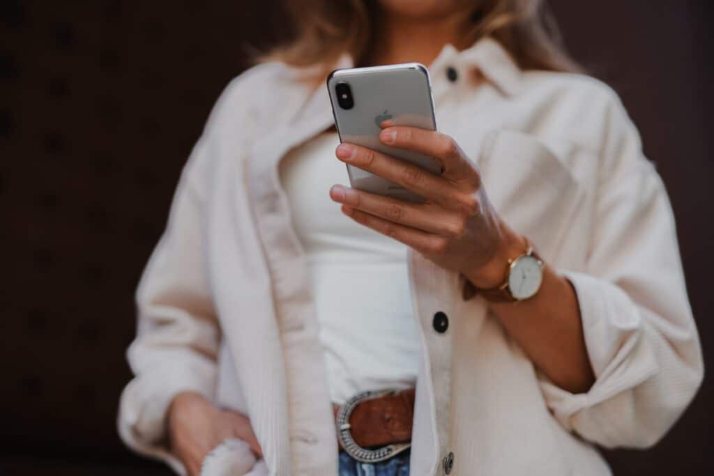 Woman in white jacket looking at an iPhone