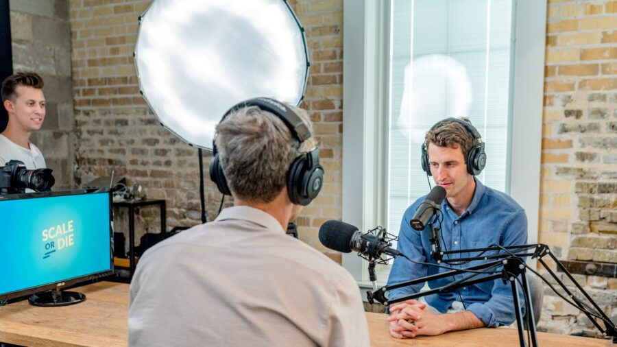 two men record a podcast in front of microphones