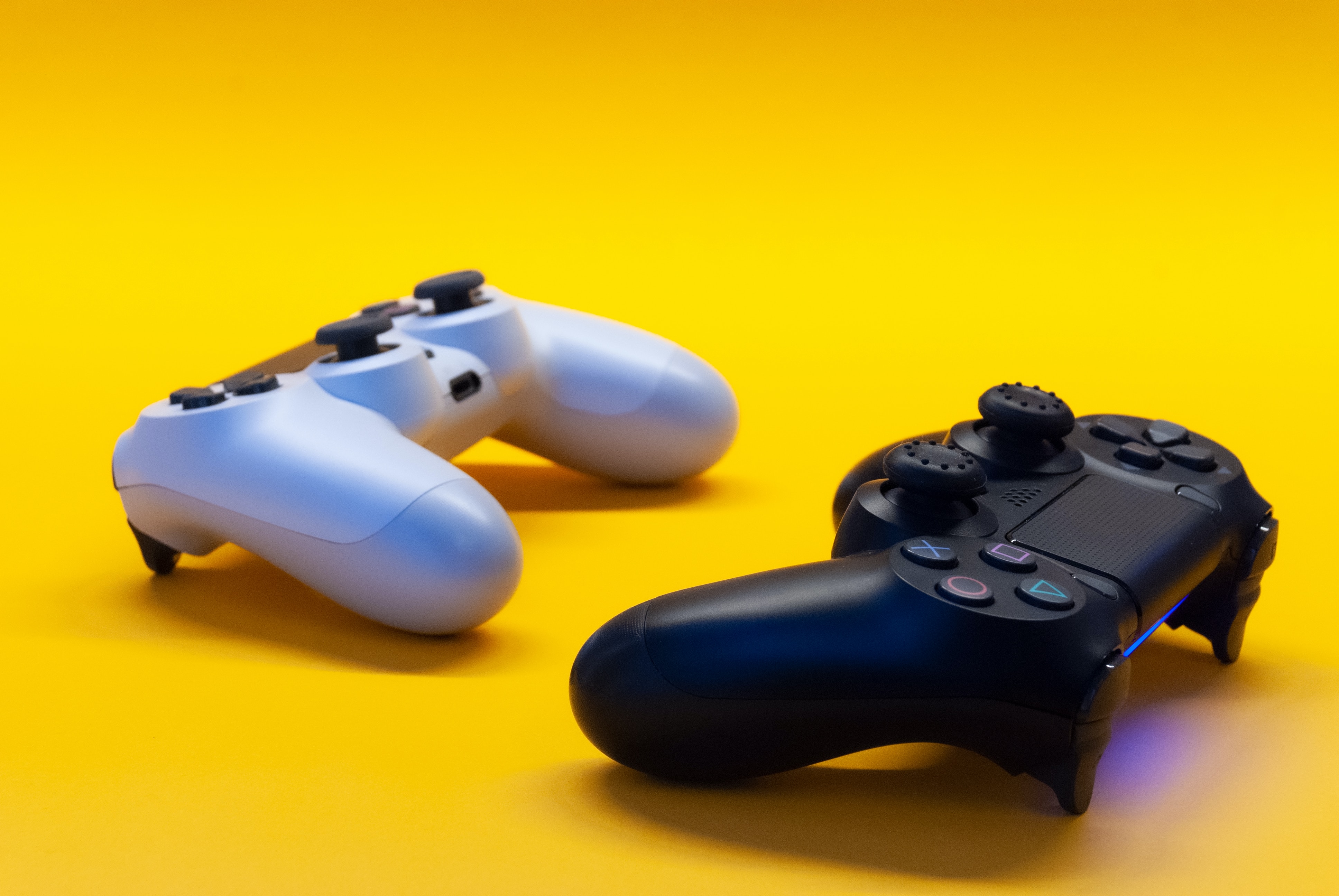 two gaming controllers in a yellow background