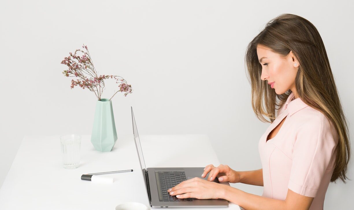 woman in a pink dress in a white office on a computer