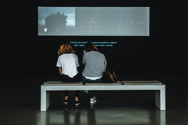two people sitting in front of a screen displaying subtitles