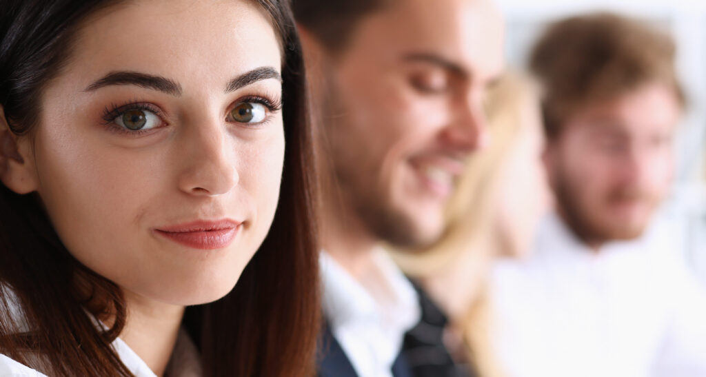 professional woman looking at the camera while other employees are in the background