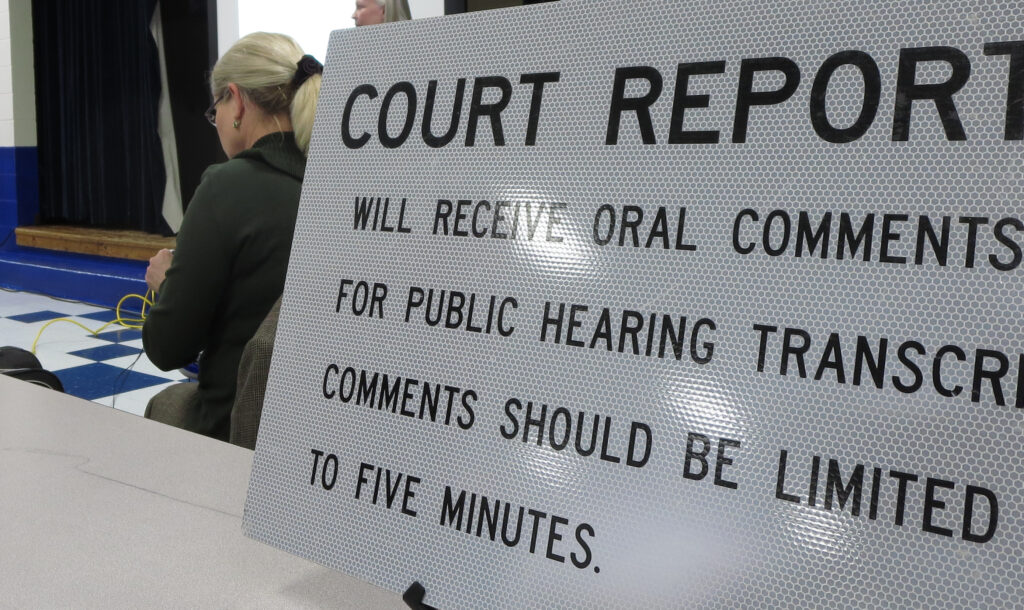 A sign in a courtroom that says "court reporters will receive oral comments for public hearings transcription comments should be limited to five minutes"