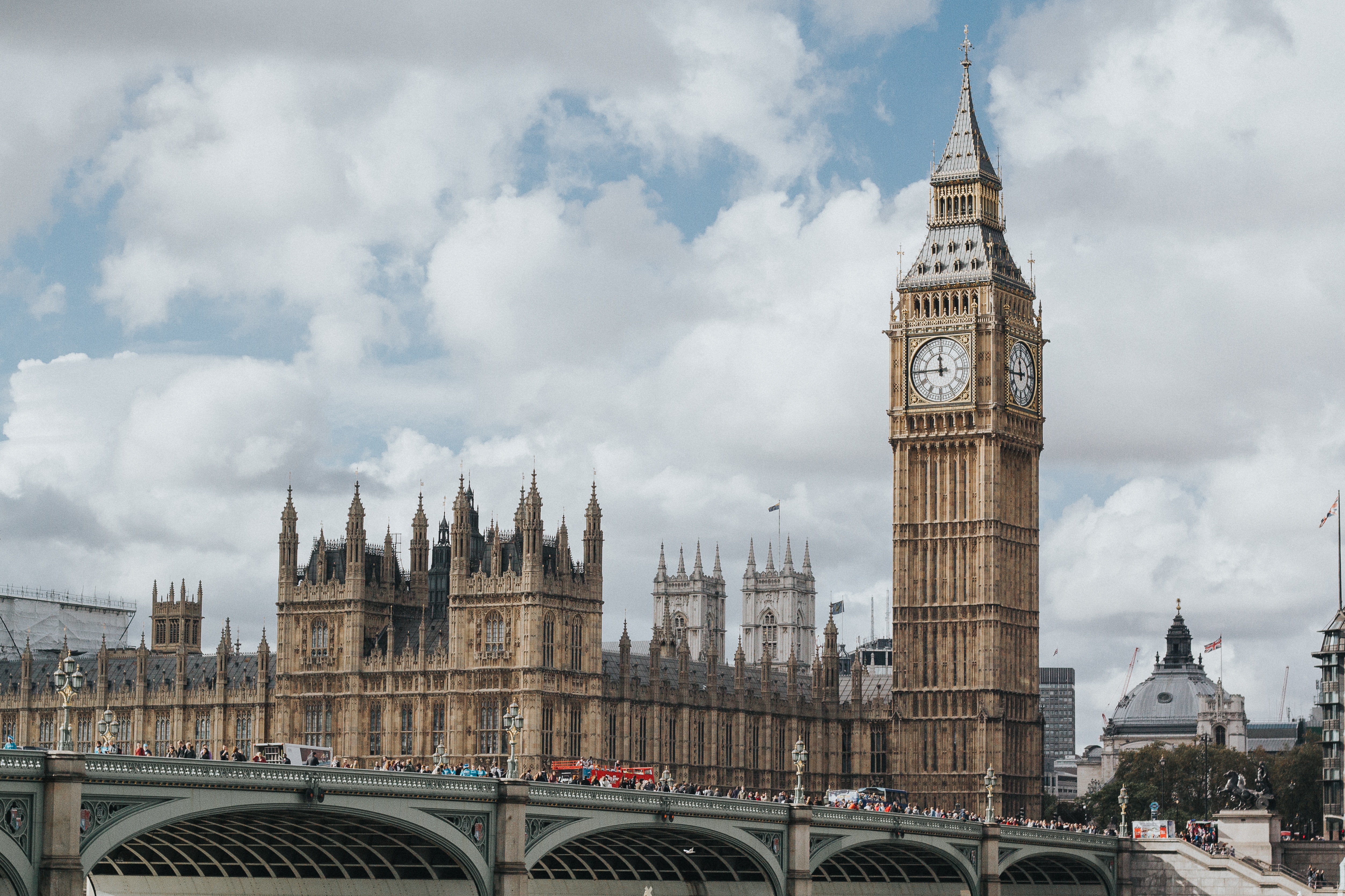 An image of the Big Ben clocktower and other iconic buildings and a bridge in London. Clouds appear in the skyline.