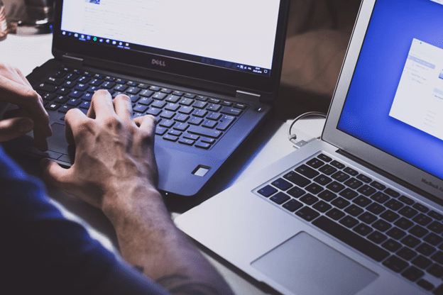 a person typing text on two computers