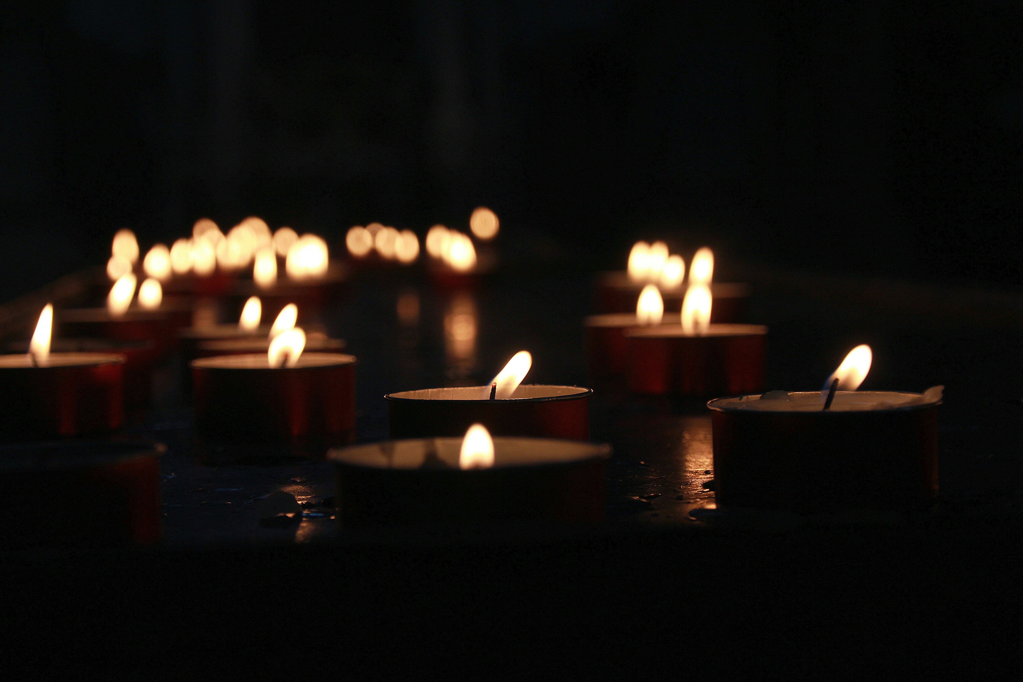 A group of memorial candles are lit in a dark room