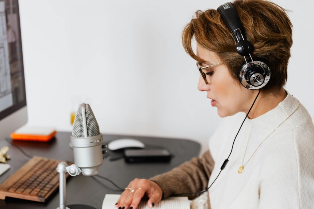 A woman focused on her laptop, wearing headphones and a headset, while working diligently.