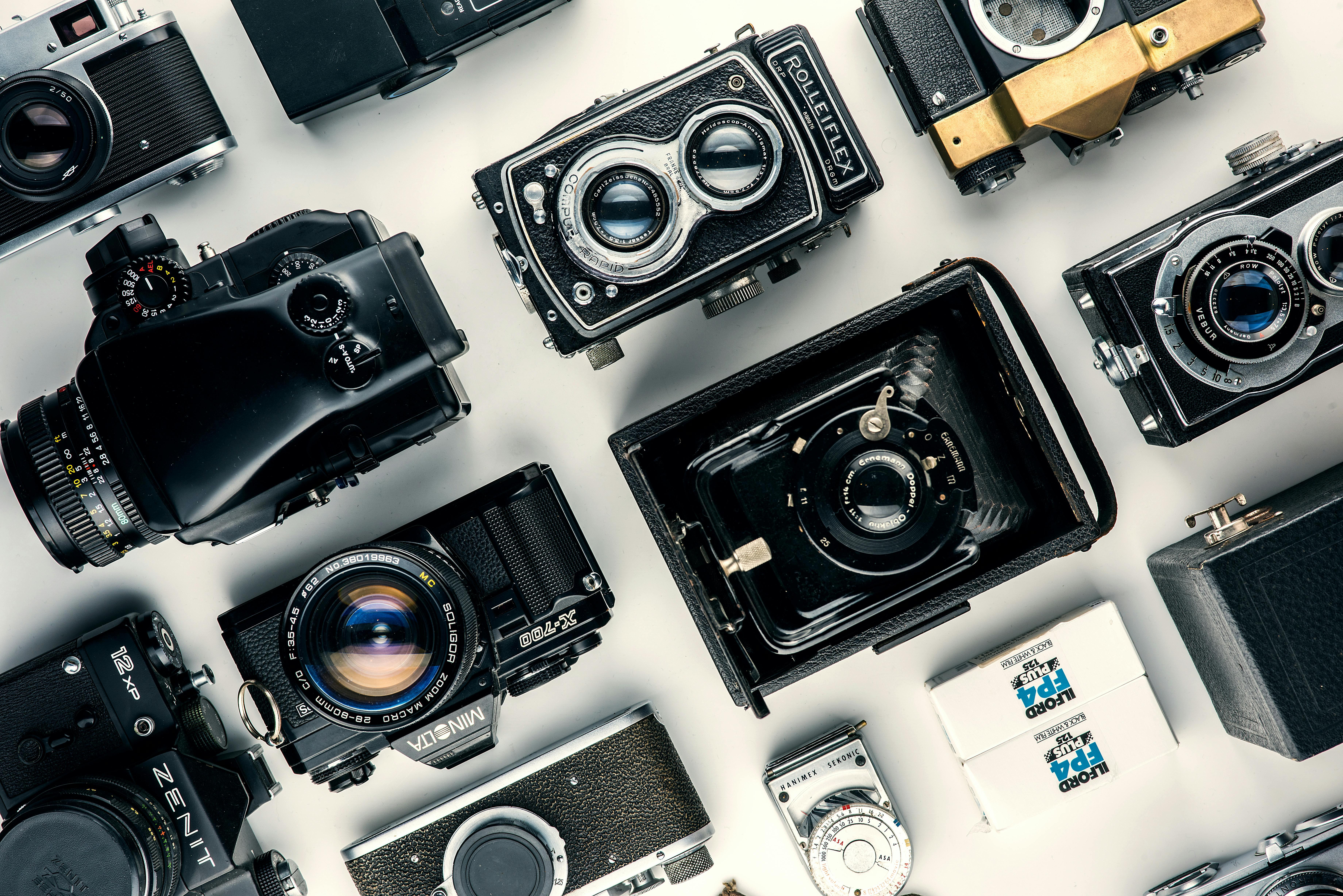A variety of vintage cameras arranged on a white surface.