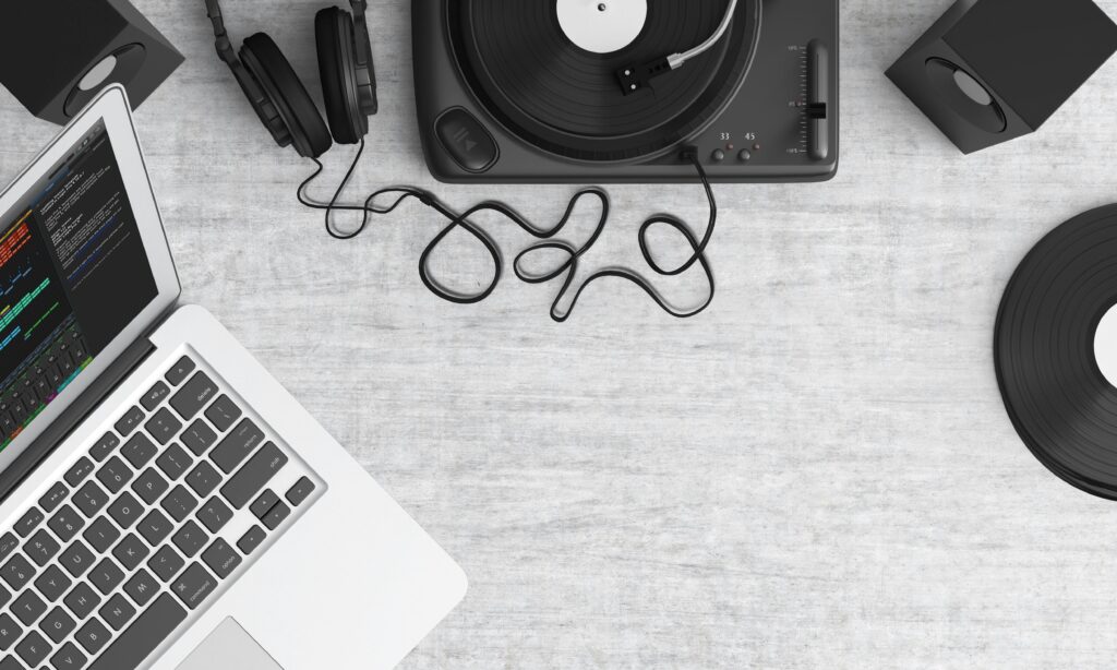 A laptop, turntable, and headphones on a desk.