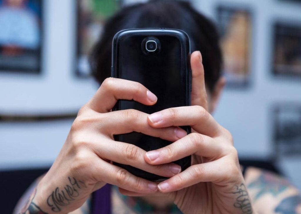 A person holding up and reading from a smartphone.