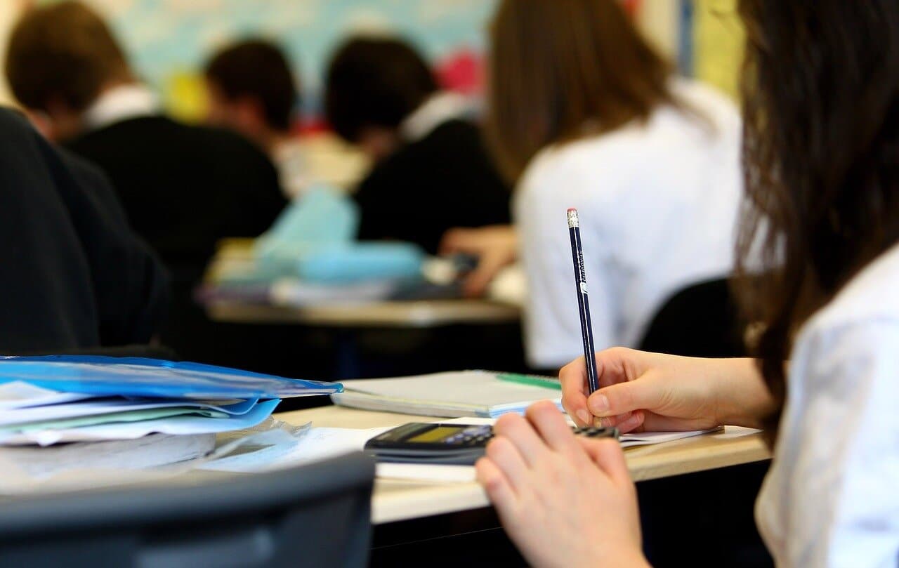 Close up of a student's hands as she takes notes in a classroom.