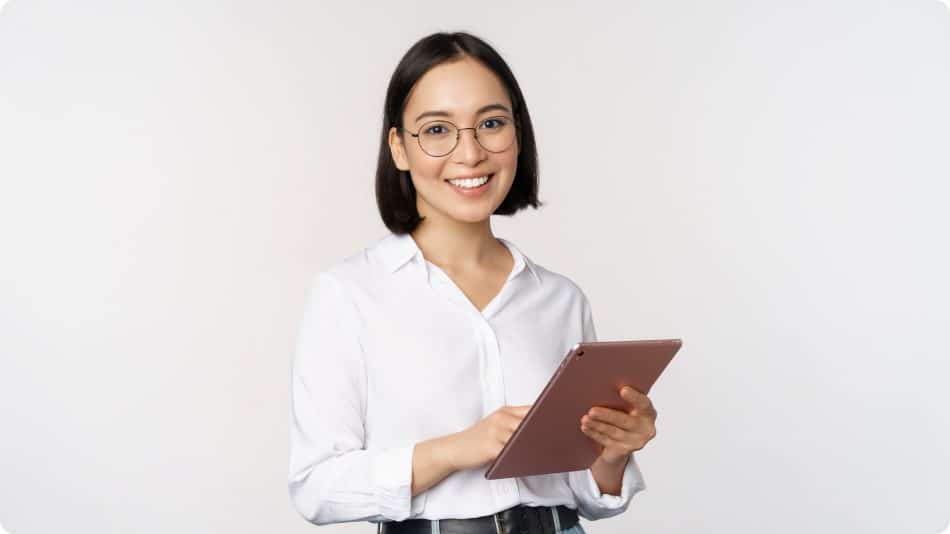 A woman smiles while holding a tablet.