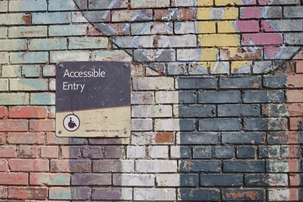 A sign posted on a colorful brick wall reads 'accessible entry.'