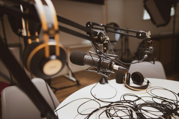 A microphone and headset and assorted wires sit on a table.