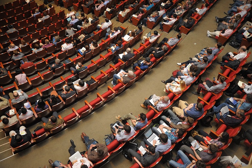 overhead view of a large audience sitting in rows of seats inside an auditorium